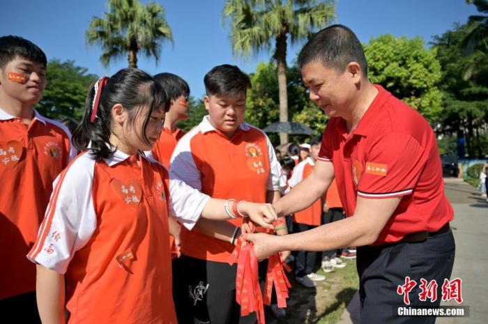 資料圖：廣西華僑實(shí)驗(yàn)高中的教師為高三學(xué)子系上紅絲帶，盼望學(xué)子高考必勝。 俞靖 攝